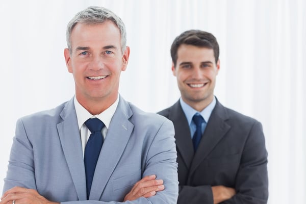 Smiling businessmen posing in bright office looking at camera